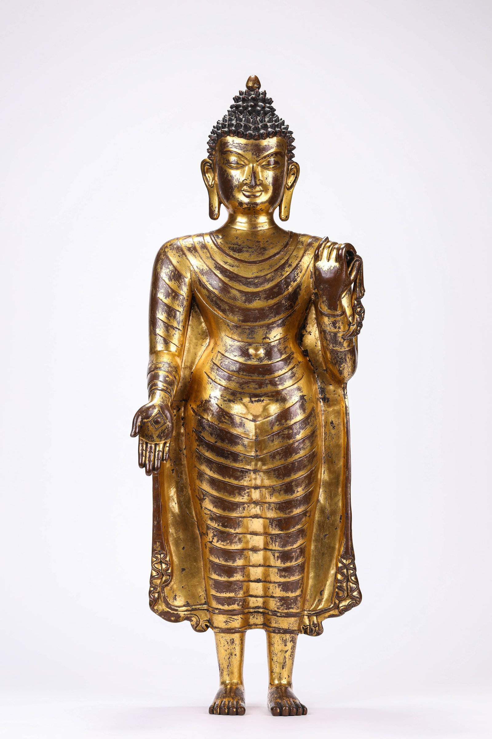 A GILT-BRONZE FIGURE OF THE SANDALWOOD BUDDHA: A GILT-BRONZE FIGURE OF THE SANDALWOOD BUDDHA Description: Dimensions: Weight: 13400 g. Length: 26 cm x Width: 16.7 cm x Height: 73 cm. All measurements are approximate.