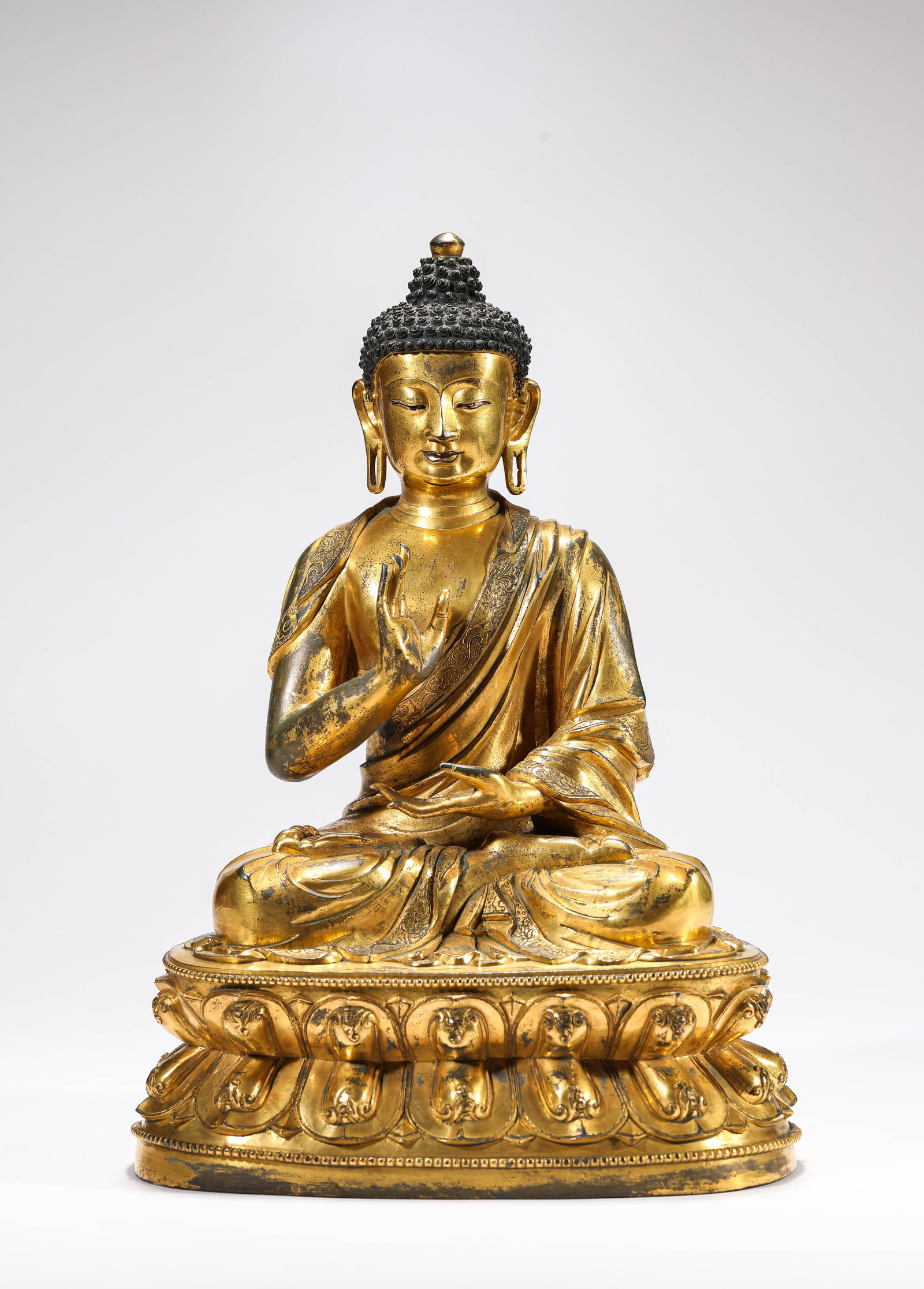 A GILT-BRONZE FIGURE OF SHAKYAMUNI: A GILT-BRONZE FIGURE OF SHAKYAMUNI Description: Dimensions: Weight: 6450 g. Length: 23.9 cm x Width: 18.5 cm x Height: 34 cm. All measurements are approximate.