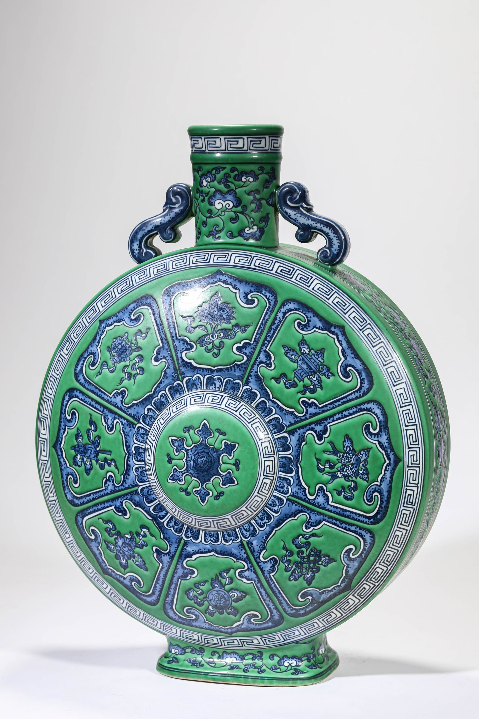A GREEN-GROUND BLUE AND WHITE 'EIGHT BUDDHIST EMBLEMS AND CLOUD HANDLES' MOONFLASK: A GREEN-GROUND BLUE AND WHITE 'EIGHT BUDDHIST EMBLEMS AND CLOUD HANDLES' MOONFLASK Description: Dimensions: Length: 36.7 cm x Width: 20.6 cm x Height: 49.5 cm. All measurements are approximate.