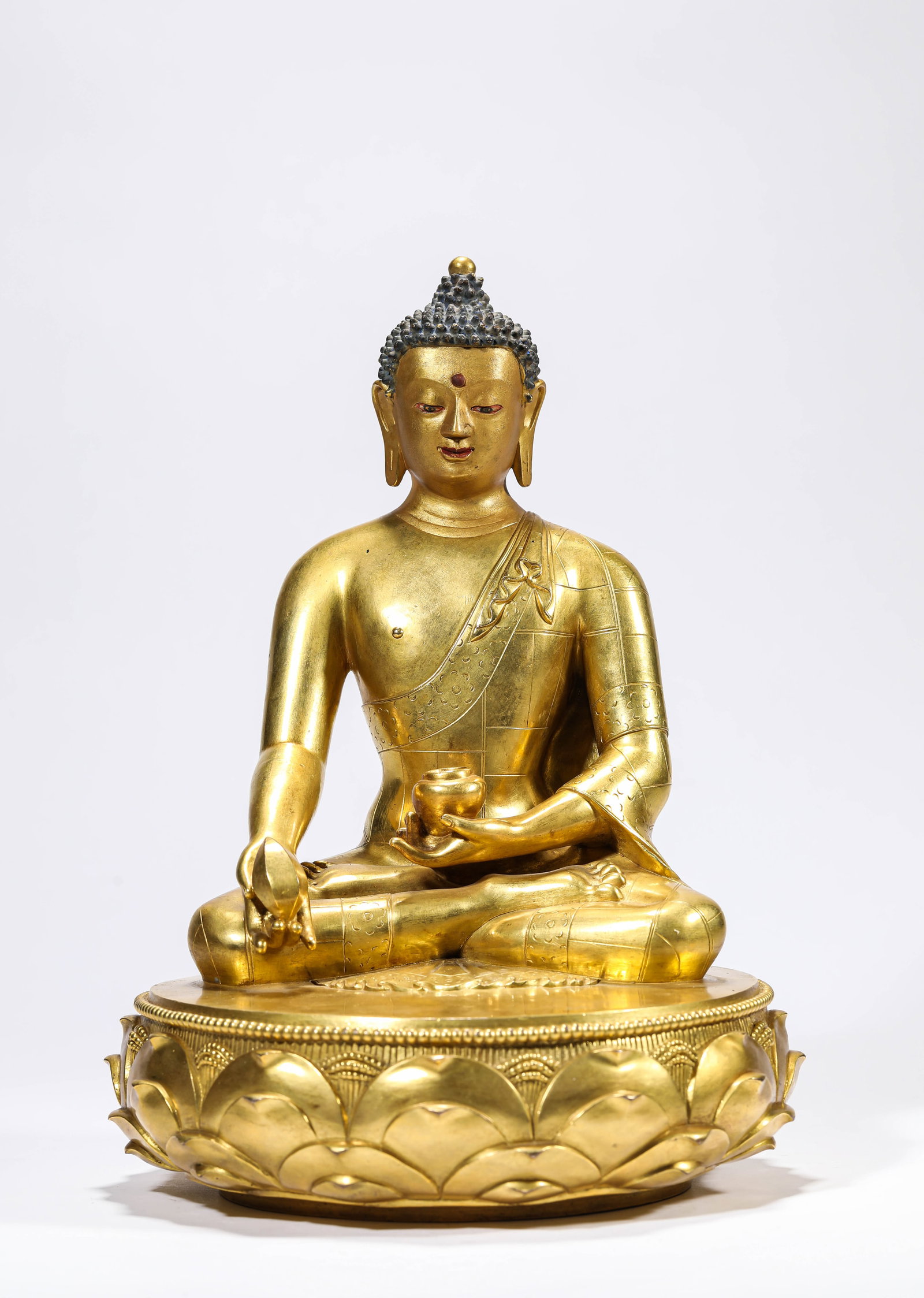 A GILT-BRONZE FIGURE OF BHAISAJYAGURU: A GILT-BRONZE FIGURE OF BHAISAJYAGURU Description: Dimensions: Weight: 6100 g. Width: 21.5 cm x Height: 29.5 cm. All measurements are approximate.
