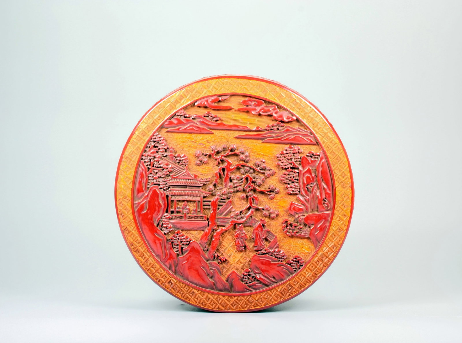 A CARVED CINNABAR LACQUER LANDSCAPE FIGURE WITH IMPERIAL POEM LACQUER BOX: A CARVED CINNABAR LACQUER LANDSCAPE FIGURE WITH IMPERIAL POEM LACQUER BOX Size:Height:7.8cm,Diam:21.5cm