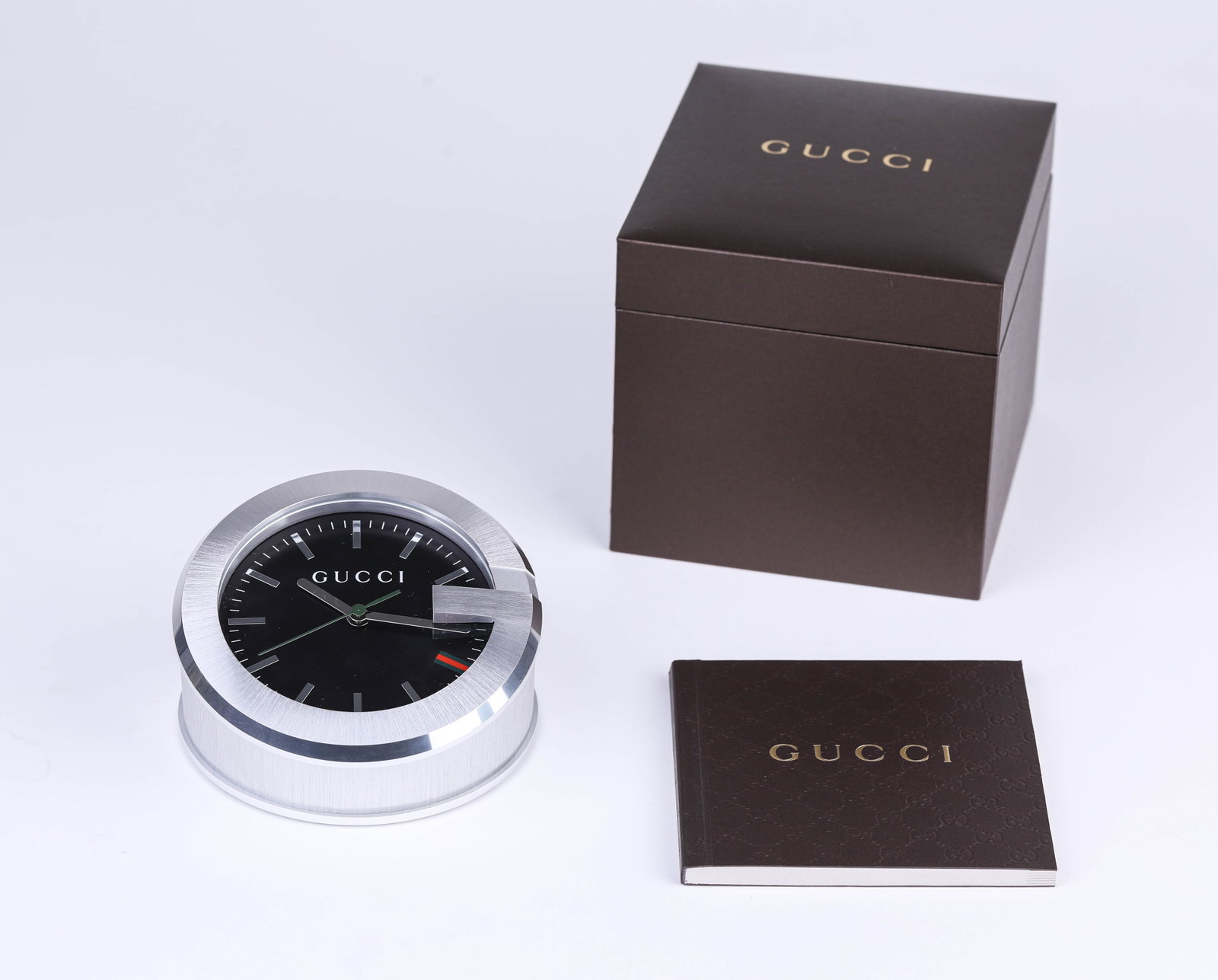 A GUCCI MANTEL CLOCK: A GUCCI MANTEL CLOCK Description: Unworn and in pristine, as-new condition.Dimensions: Weight: 434 g. Width: 10.1 cm x Height: 6.4 cm. All measurements are approximate.