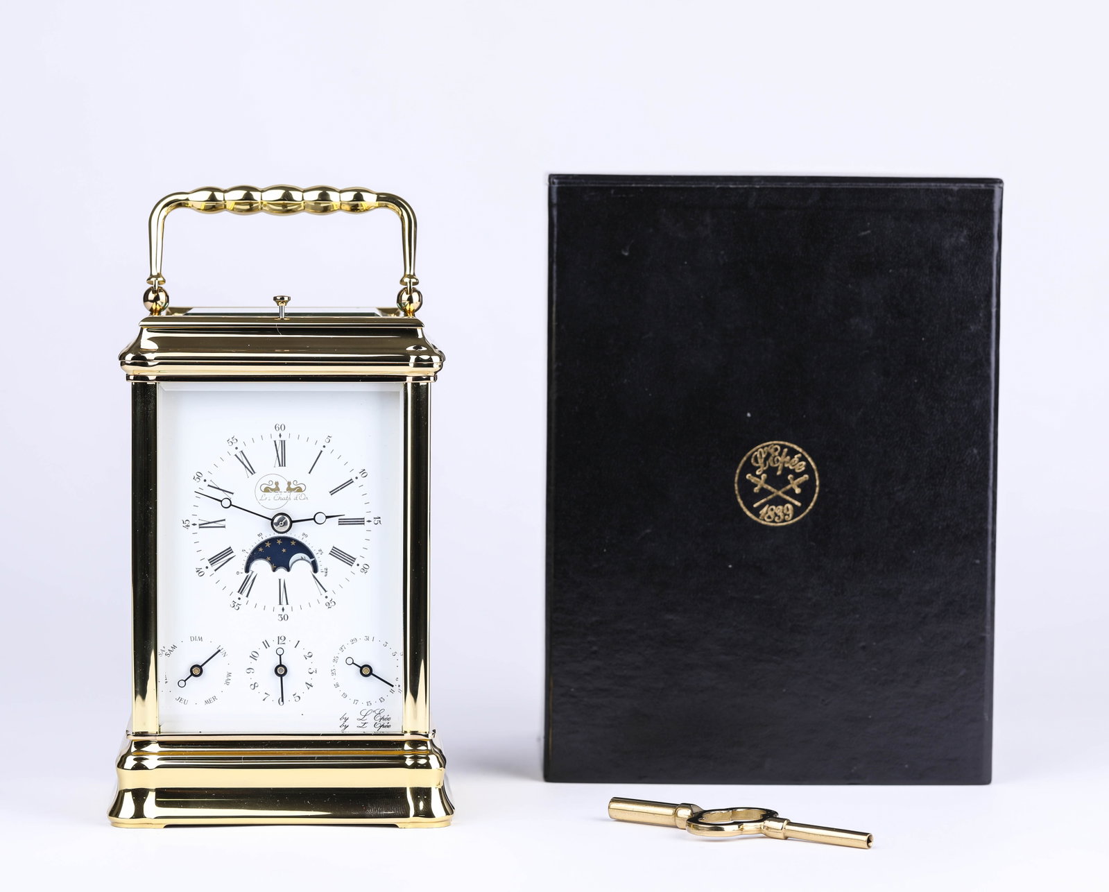 A LE PHARE CARRIAGE CLOCK: A LE PHARE CARRIAGE CLOCK Description: Comprising date, day, and moon-phase indications.Dimensions: Weight: 1866 g. Length: 9.8 cm x Width: 8.7 cm x Height: 18 cm. All measurements are approximate.