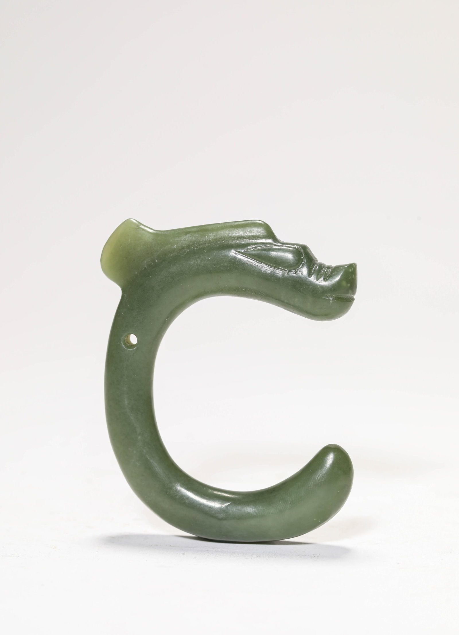 A 'C'-FORM JADE DRAGON: A 'C'-FORM JADE DRAGON Description: Dimensions: Length: 6.7 cm x Width: 1.4 cm x Height: 8.2 cm. All measurements are approximate.