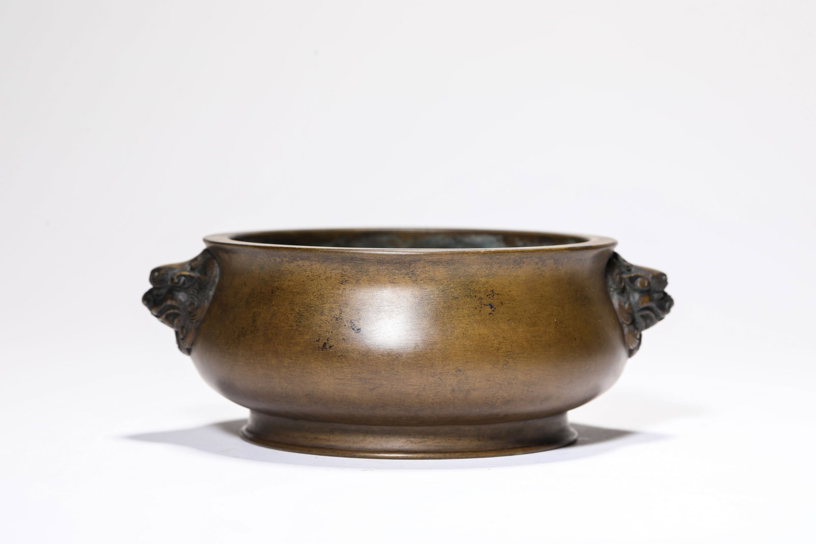 A BRONZE 'LION-HEAD HANDLES' CENSER: A BRONZE 'LION-HEAD HANDLES' CENSER Description: Dimensions: Weight: 1134 g. Length: 16.1 cm x Width: 13.3 cm x Height: 6 cm. All measurements are approximate.