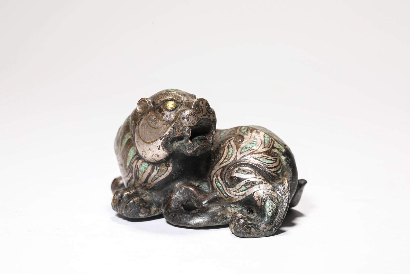A GOLD AND SILVER-INLAID BRONZE 'AUSPICIOUS BEAST': A GOLD AND SILVER-INLAID BRONZE 'AUSPICIOUS BEAST' Description: Dimensions: Weight: 513 g. Length: 10.1 cm x Width: 8.1 cm x Height: 6.1 cm. All measurements are approximate.