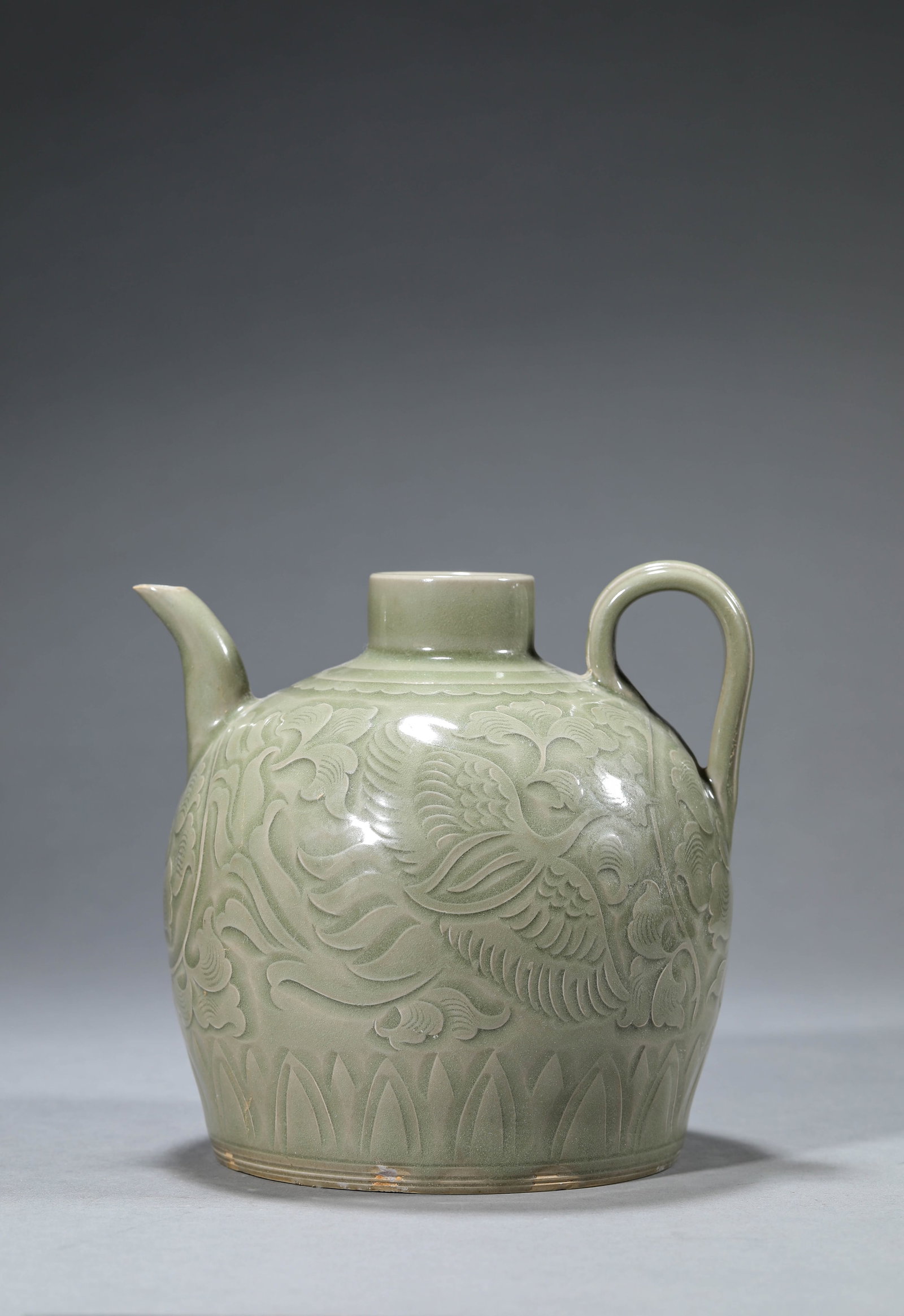 A YAOZHOU-TYPE 'CARVED PHOENIX AMIDST FLOWERS' EWER: A YAOZHOU-TYPE 'CARVED PHOENIX AMIDST FLOWERS' EWER Description: Dimensions: Length: 16.8 cm x Width: 15.3 cm x Height: 15.8 cm. All measurements are approximate.