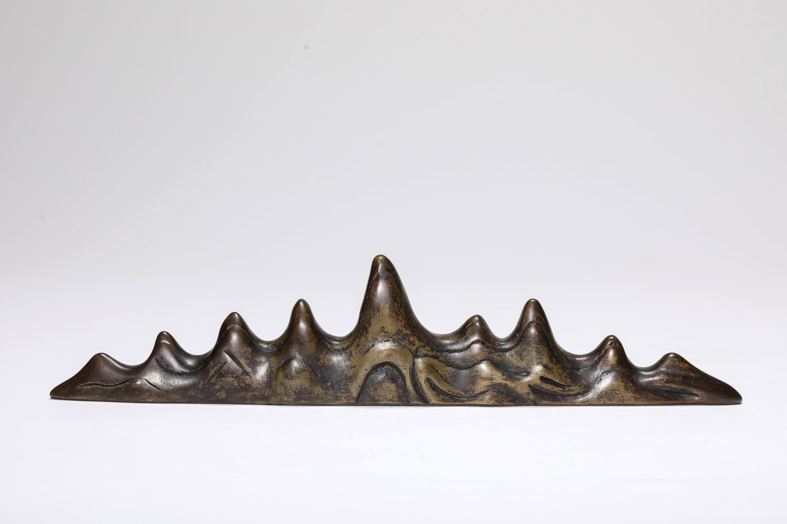 A BRONZE 'MOUNTAIN' ORNAMENT: A BRONZE 'MOUNTAIN' ORNAMENT Description: Dimensions: Weight: 420 g. Length: 19.2 cm x Width: 2.1 cm x Height: 4.2 cm. All measurements are approximate.