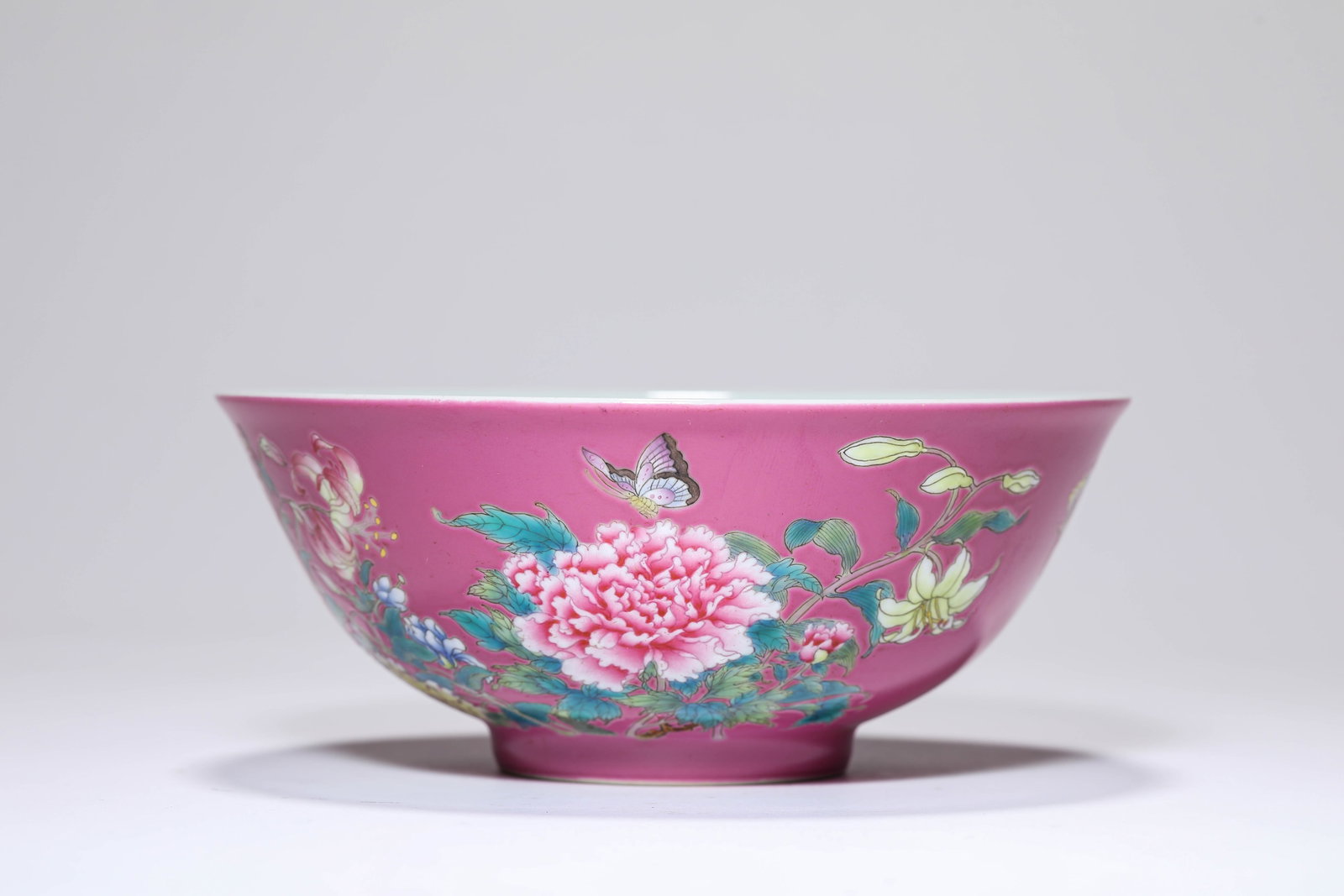 A ROUGE-GROUND FAMILLE-ROSE 'BUTTERFLIES AMONG FLOWERS AND POEM' BOWL: A ROUGE-GROUND FAMILLE-ROSE 'BUTTERFLIES AMONG FLOWERS AND POEM' BOWL Description: Dimensions: Width: 15 cm x Height: 6.3 cm. All measurements are approximate.