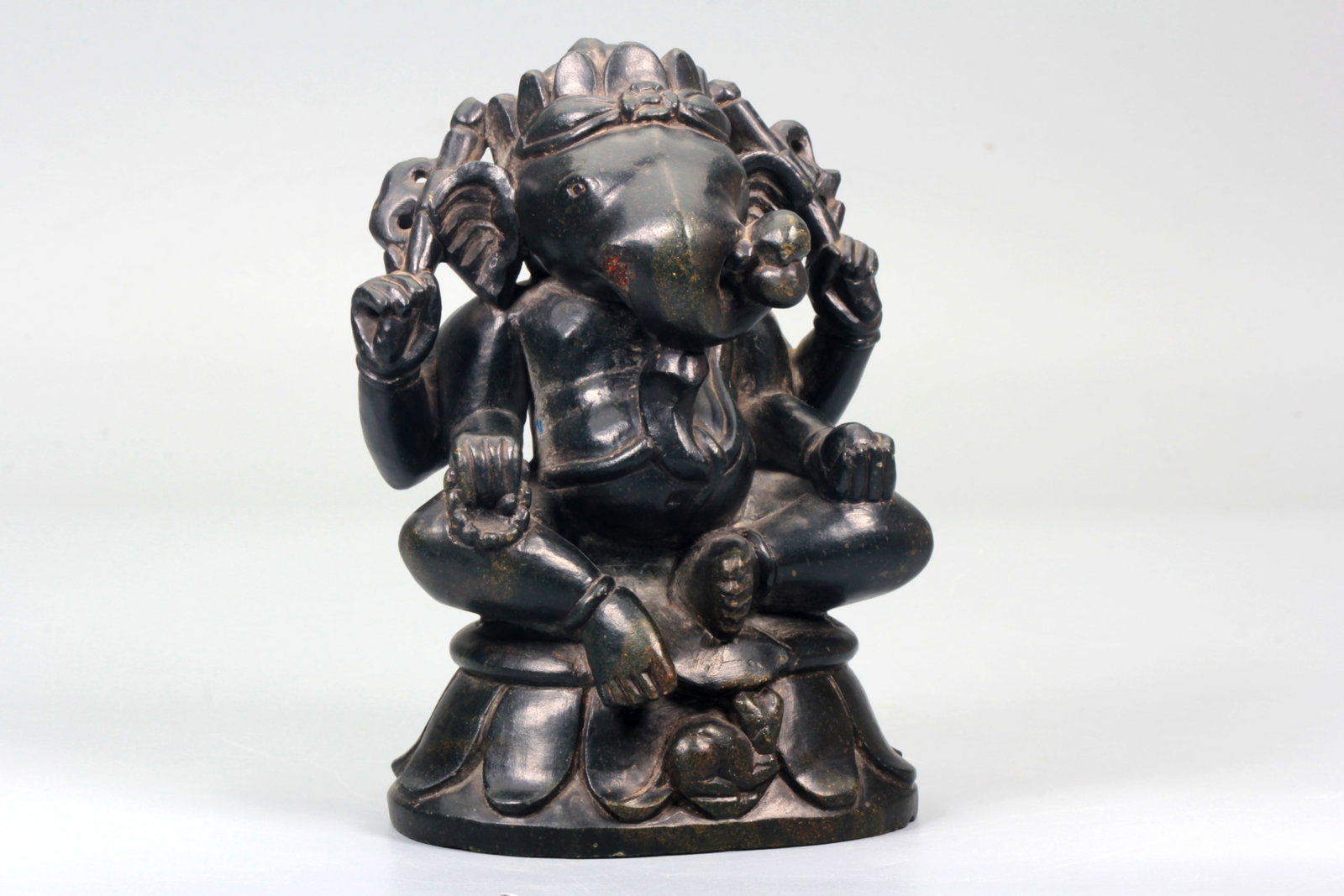 A BLACK STONE CARVED FIGURE OF GANESHA: A BLACK STONE CARVED FIGURE OF GANESHA Height:13.6cm,Width:9.5cm;Weight:999g