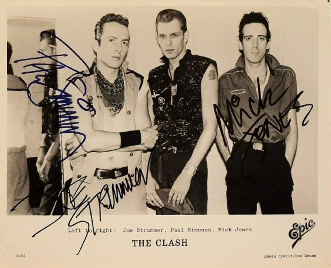 The Clash signed promo photo: 8 in. by 10 in. The Clash black and white promotional photo autographed by Joe Strummer, Mick Jones and Paul Simonon.