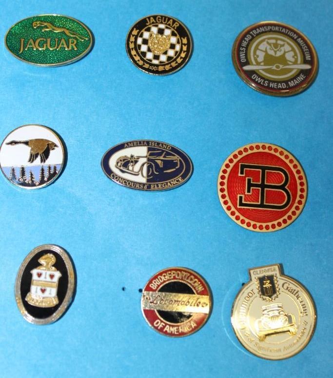 Group of Nine Automobile Manufacturer Pin Badges: 4.5" x 5"; Cord, Bugatti, Wills Sainte Claire, Locomobile, Jaguar, and Concours Show