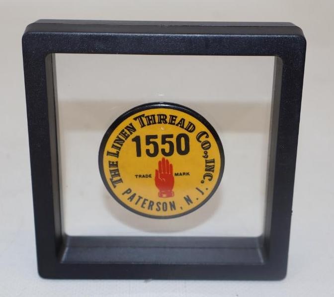 THE LINEN THREAD COMPANY EMPLOYEE BADGE WITH HAND GRAPHIC.: 1.75" DIAMETER 1920'S CELLULOID OVER TIN EMPLOYEE BADGE FOR THE LINEN THREAD COMPANY, PATTERSON, N.J. CONDITION: OUTSTANDING CONDITION THROUGHOUT WITH BRIGHT COLOR & GLOSS SHOWING NO NOTABLE WEAR. BAC