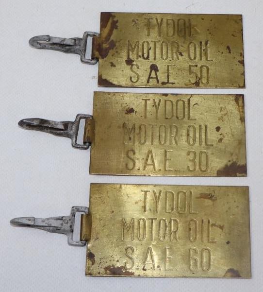 COLLECTION OF 3: TYDOL MOTOR OILS STAMPED BRASS OIL BARREL TAGS WITH ORIGINAL CLIPS.: 3.5" X 2" EACH. 1930'S BRASS TAGS EACH SHOWING TYDOL MOTOR OIL STAMPED INTO THE FACE AS WELL AS THE OIL GRADE. EACH TAG SHOWS ORIGINAL CLIPS USED FOR HANGING FROM OIL BARRELS. CONDITION: ORIGINAL AND 