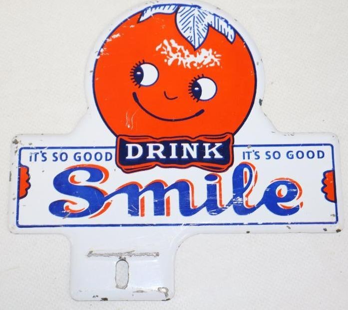 Drink Smile "It's So Good" Orange Soda Advertising License Plate Topper: In nice condition with light scratching throughout. 6.25" x 6"