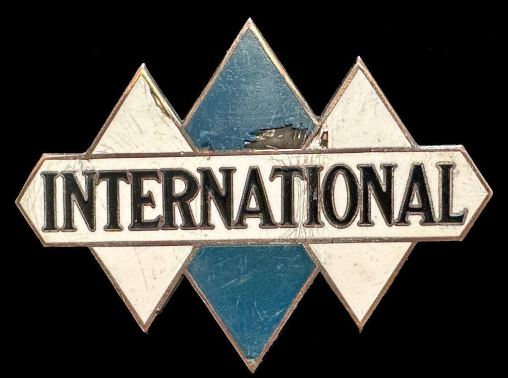 International Radiator Emblem: c1923 - 1933 International radiator emblem. This emblem has a DL Auld maker's mark and measures approximately 3.5" wide by 2.6" high.
