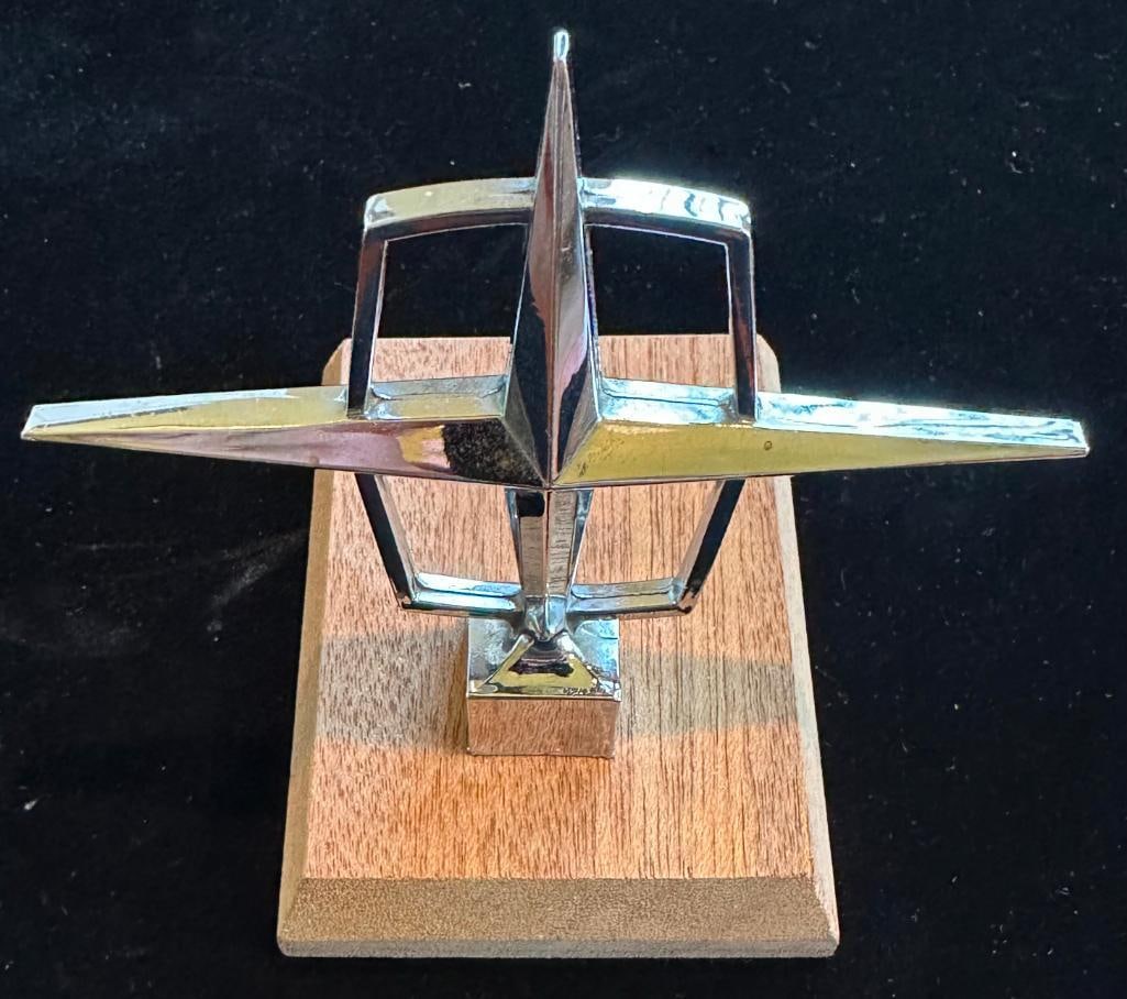 Lincoln Continental Hood Ornament: 1965 - 1967 Lincoln Continental Hood Ornament. Mounted to wood base. This item measures approximately 4.5" wide by 3.4" high.