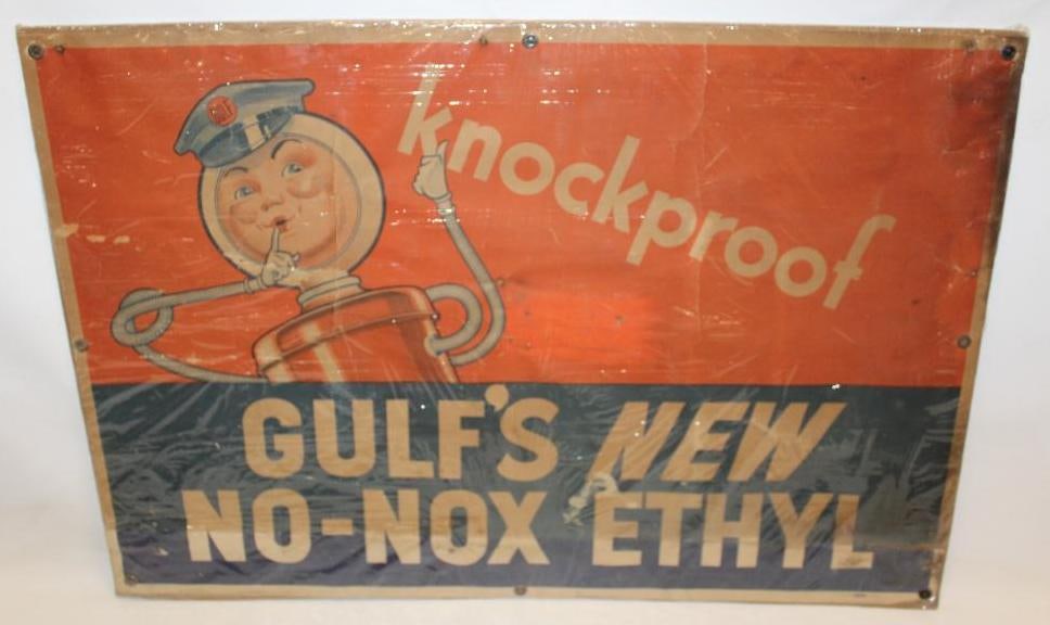 Gulf Knockproof Advertising Cardboard Poster Sign: This cardboard sign is shrink wrapped to a piece of cardboard. It is marked John Igelstrom Company. The sign shows some discoloration and creases throughout. There is also a tear along the lower right