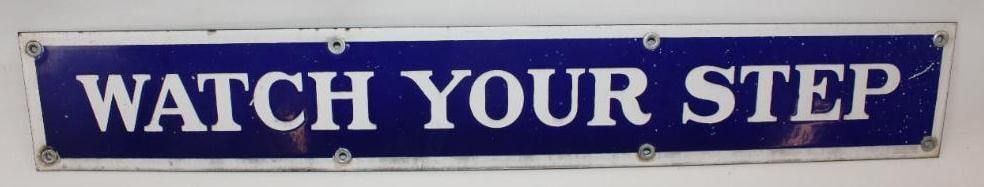 Watch Your Step Railcar SSP Porcelain Sign: This sign has some slight wear throughout. There are also several small imperfections to the blue porcelain. This sign measures 21" x 3.25" and is graded an 8.
