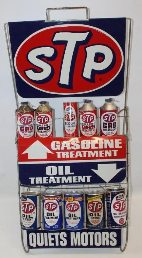 STP Gasoline and Oil Treatment Metal Advertising Display Rack with STP Cans: This is a metal display rack with three metal signs. Each of the signs have good color and gloss throughout with light wear. Some of the cans on the rack are full and some are empty. Some of the cans