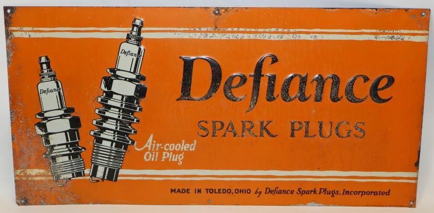 Defiance Spark Plugs SST Embossed Advertising Sign: This sign is marked American Art Works Inc. It displays well with some surface rust spots to the field with slighly more to the lower left corner. This sign measures 23.75" x 11.75" and t is graded a 