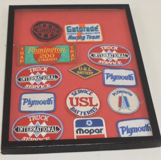 Group of 13 Automobile Related Shirt Patches Displayed In Glass Riker Case: Case Measures 16x12
