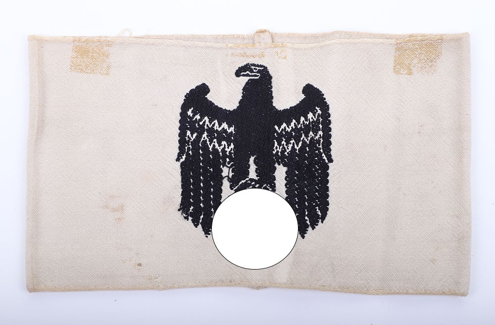 GERMAN WWII ARMED FORCES ARMBAND: GERMAN WWII ARMED FORCES ARMBAND, a black embroidered down-winged eagle on white cotton, has a few small holes & a few tape marks (it was removed from a scrap album), G+