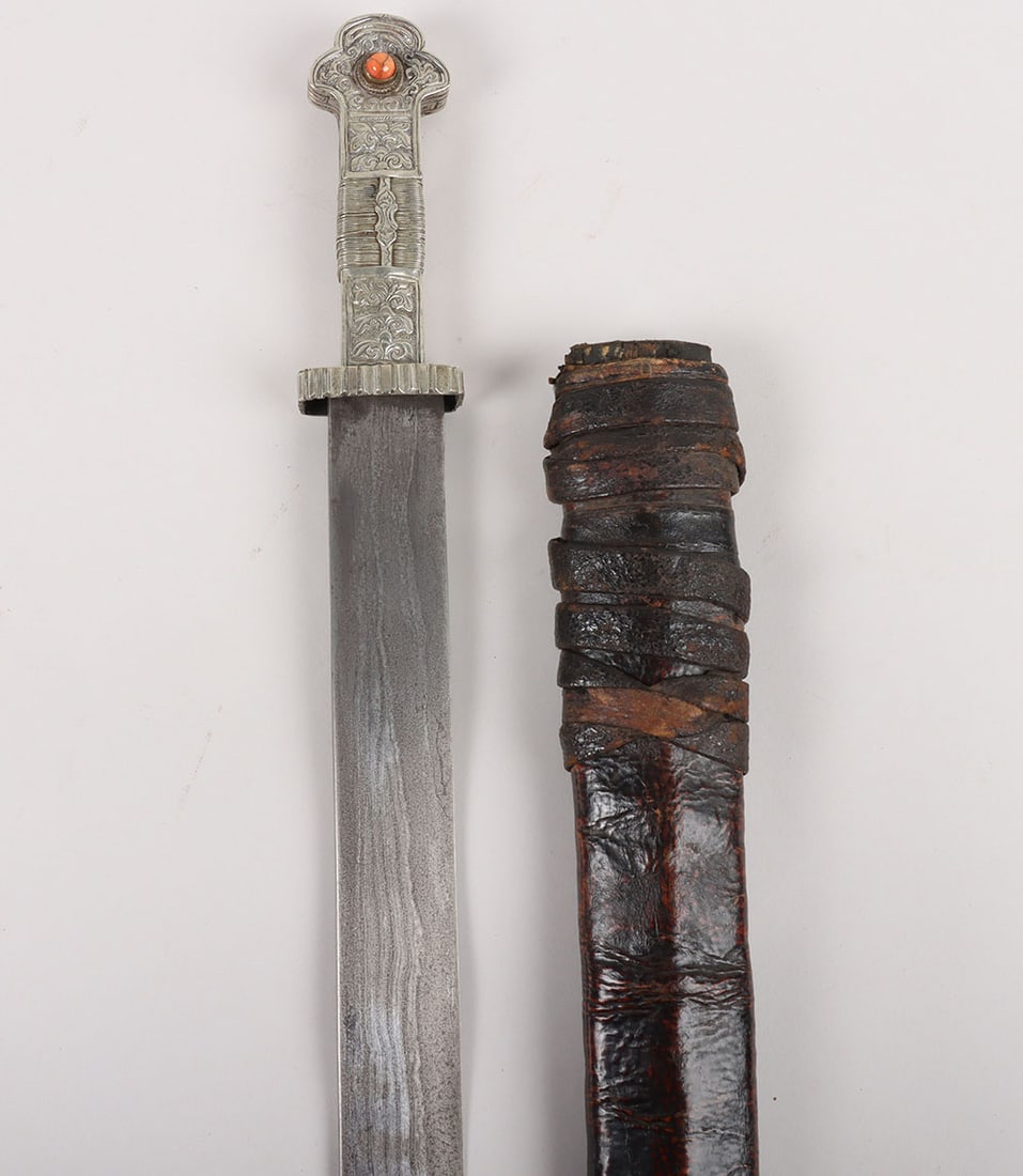 Tibetan or Bhutanese Sword, 19th Century: Tibetan or Bhutanese Sword, 19 th Century , broad straight single edge blade 72.5cms forged with ‘needle’ pattern, hatchet tip, nickel hilt chased with foliate decoration, nickel wire binding and
