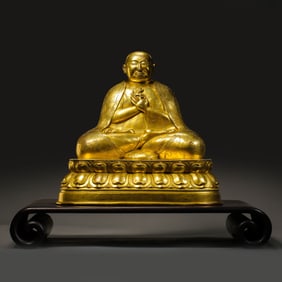 A CHINESE MING DYNASTY GILT BRONZE SEATED GURU BUDDHA