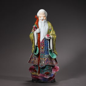 QING DYNASTY. A PAINTED PORCELAIN FIGURE STANDING ON A TREE