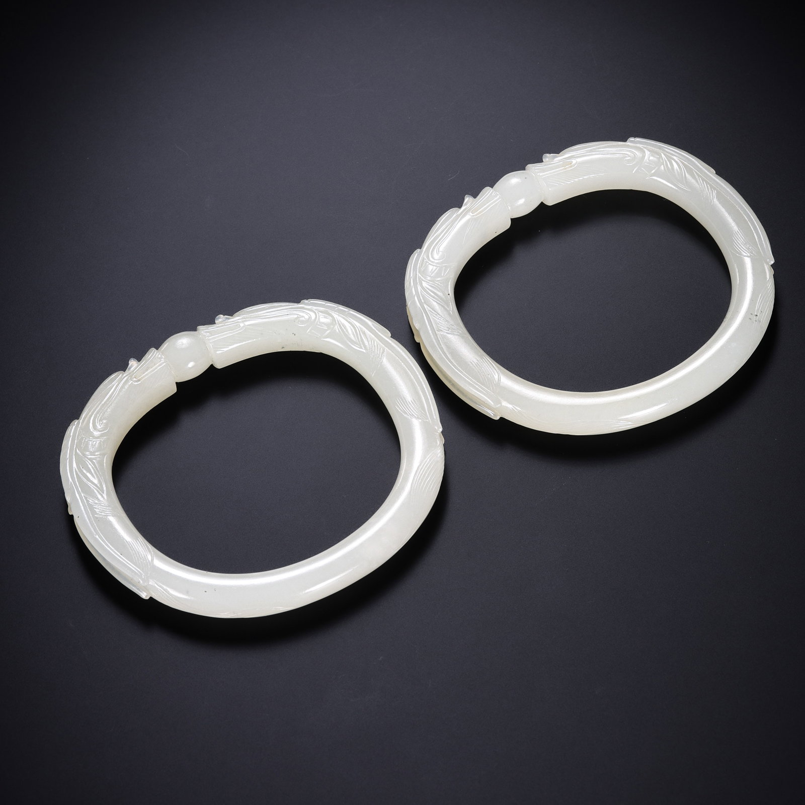 Pair of Hetian Jade Bracelets with Dragon-Head Decoration, Qing Dynasty: approx. 7.5 cm (3.0 in), Total weight: approx. 77 g, 18th–19th CenturyCondition & Provenance:?In good condition overall. The jade is pale, smooth, and lustrous, with the bracelet forms well preserve