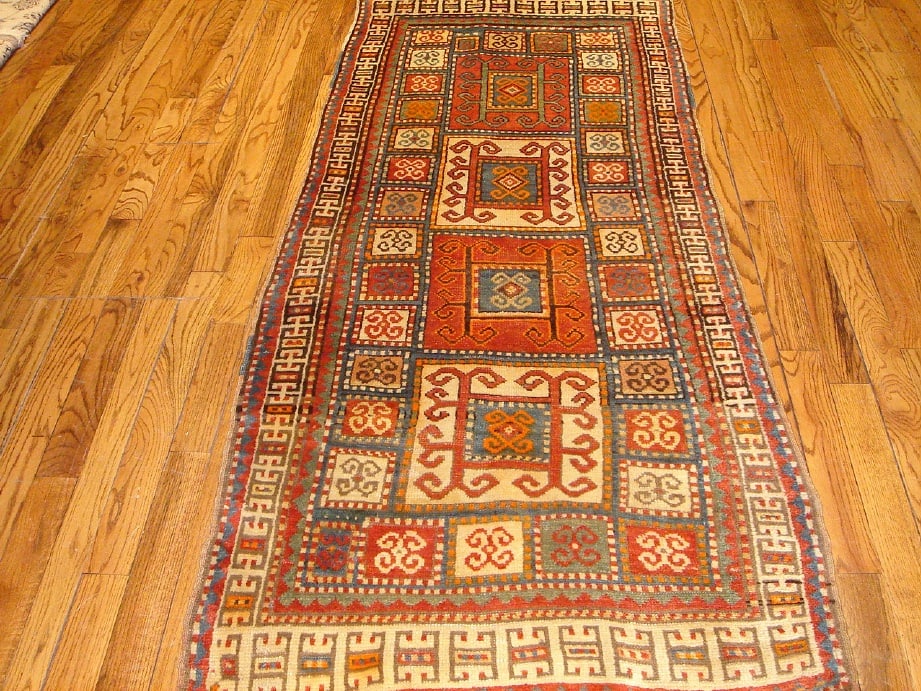 Antique Caucasian Bordjalou Kazak Hand-Knotted Wool Runner: This exceptional Antique Caucasian Bordjalou Kazak runner showcases the bold tribal artistry and enduring craftsmanship of the southern Caucasus. Hand-knotted from hand-spun wool, the rug features a s