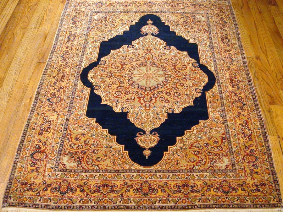 Antique Tabriz Hand-Crafted Rug, Northwest Persia, 4' 2'' X 5'10'': The deep indigo field centers an elaborate medallion surrounded by finely drawn scrolling vines, palmettes, and delicate floral ornamentation rendered in warm tones of navy and rust. The elegant contr