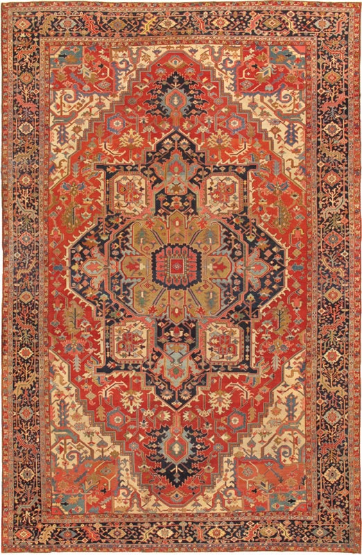 Antique Serapi Rug, Northwest Persia, 12' 7'' X 19' 7'': The striking field is dominated by a monumental geometric medallion set against a rich brick-red ground, surrounded by angular vinery, stylized palmettes, and expressive tribal motifs. Rendered in a p