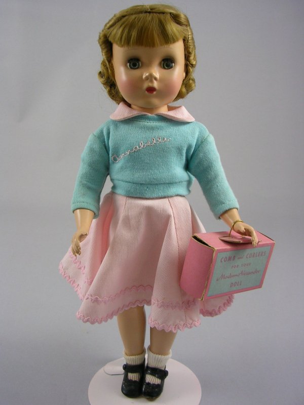 14" KATE SMITH'S "ANNABELLE" BY ALEXANDER: Five-piece body, Maggie face, light brown wig, sleep eyes. Light blue name sweater over tagged pink dress with rick-rack trim, side-snap shoes. Includes filled comb and curlers box. Circa 1952.