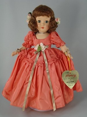 14" HARD PLASTIC HONEY FORMAL BY EFFANBEE: Hard plastic five-piece body, brown mohair wig in original set. Wearing original coral taffeta ball gown with rose trim and silk ribbon ties, matching undergarments, black satin shoes. Effanbee heart-