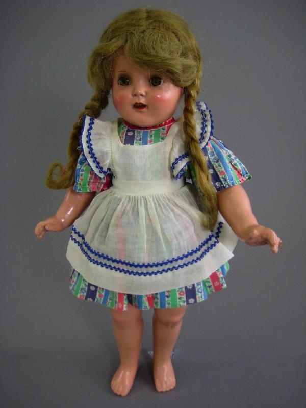 17" ALL ORIGINAL COMPOSITION MCGUFFY ANNA TYPE: Marked "18" on back. Blond human hair wig in original braids, brown sleep eyes, five piece strung body, flowered cotton print dress and onsie with organdy pinafore. No shoes/socks. Some damage at side