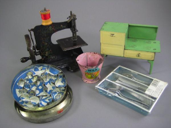 ANTIQUE TOY SEWING MACHINE, STOVE AND OTHER ITEMS: Black flower stencilled sewing machine is #10858 and wheel turns freely. Green and cream stove is 4 1/2" H and has working drawer. Original tin German cookie cutters. Marx milk pail. Unopened set of u