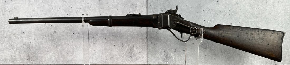 Sharps New Model Cartridge Conversion Carbine: Saddle Ring Carbine. .50-70 Cal. 22" barrel. Lawrence patent rear sight. Action has conversion breech block & retains the Sharps primer feed on the lock. Left side has a saddle ring & bar. Walnut fore