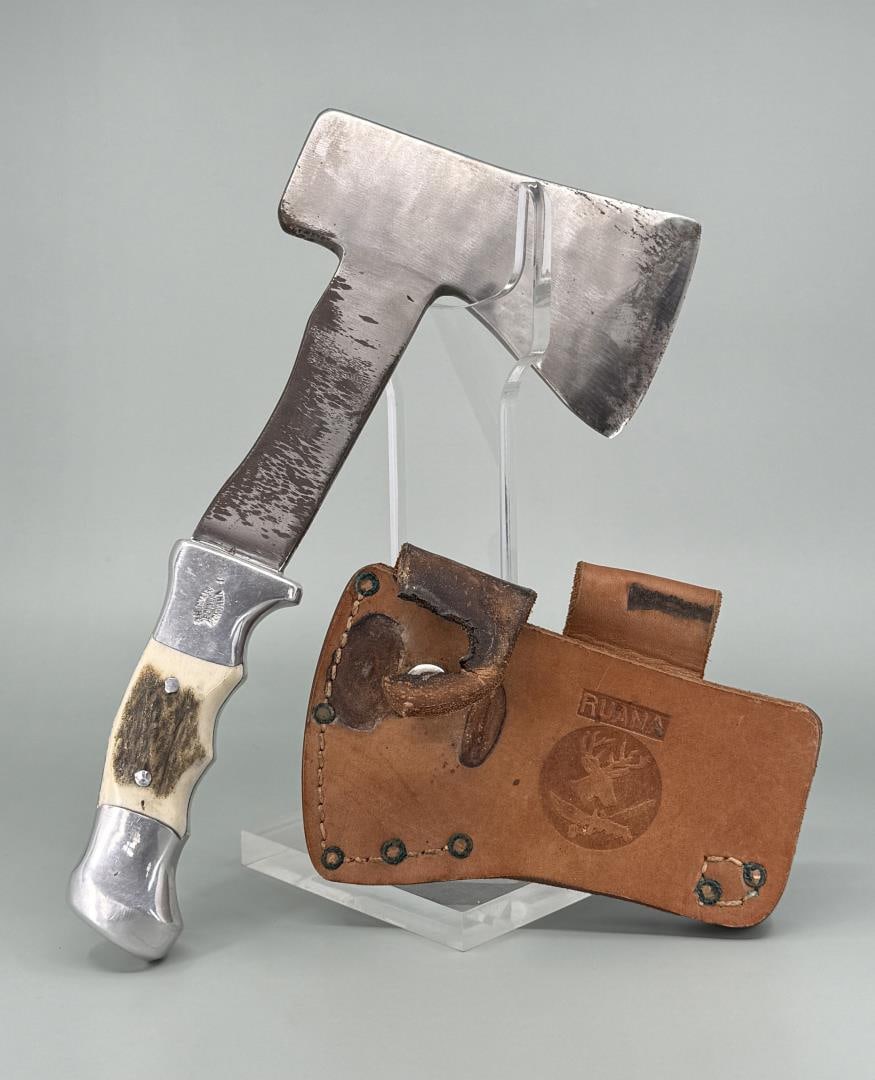 Rudy RH Ruana Bonner Montana Camp Hatchet: 22a M Stamp, some damage to the sheath clasp, some carbon staining. 10 1/2" long.