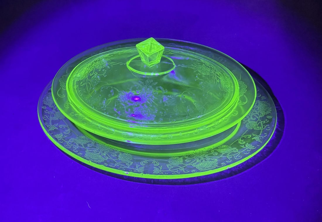 Group of Hazel Atlas Uranium Glass Dishware: Plate, Vegetable Dish, and Lid. The Plate is 11" by 8 1/8". The Vegetable Dish and Lid are 9 1/8" long by 6 3/4" wide.