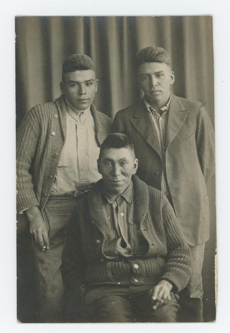 RPPC Postcard of Native American Indian Men: Men are holding cigarettes and are dressed in Reservation attire.