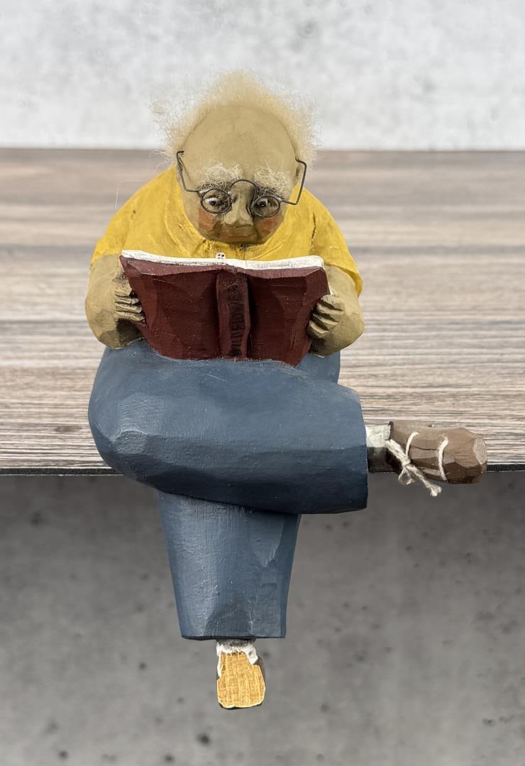 Paige Koosed Wood Carved Sitting Man: 6 1/4" by 4 1/4" by 3 7/8". 1990. Signed underneath. Missing left shoe.