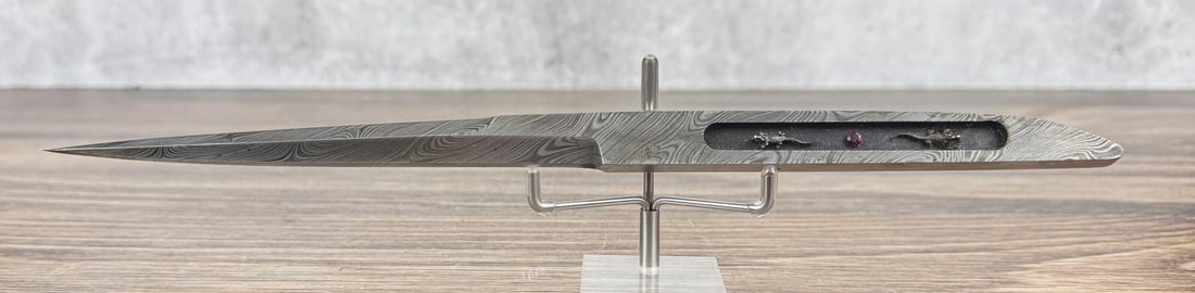 JW Townsend Montana Damascus Steel Dagger: 11 7/8" long. Decorative alligator inset handle with a ruby. Townsend was originally from Montana but moved to Louisiana and passed away in 2010.