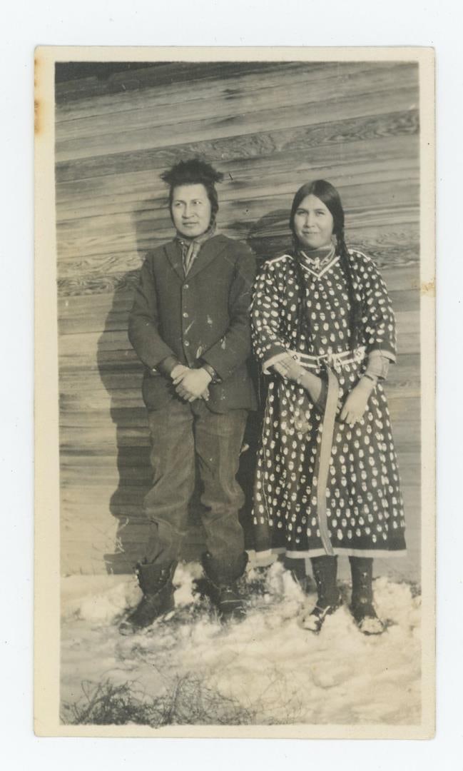 Crow Indians in Elk Tooth Dress Montana Photo: Title on Back: Crow Couple showing off Elk Tooth dress to wife. 2 1/2" by 4 1/4" Provenance: Aline Natalie Burgess Claremont Los Angeles, daughter of James Gregor Burgess builder of the Burgess Baptis