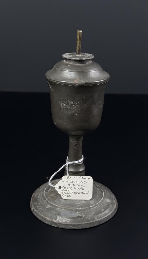 19th Century Pewter Tulip Oil Lamp: 8" by 4 1/4" by 4 1/4". Has a single wick fluid burner, tulip shade font, and a trumpet stem and base.
