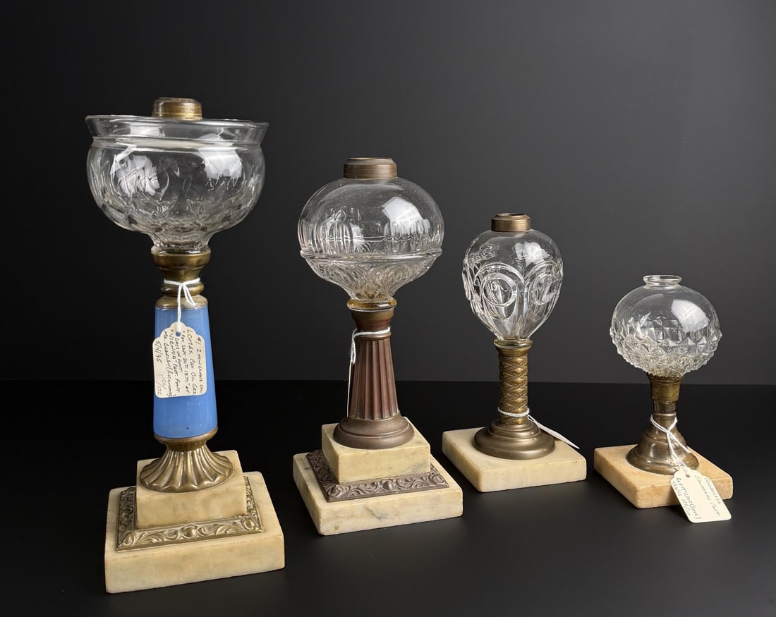 19th Century Marble Base Whale Oil Lamps: Largest is 13 1/2" tall with a 4 1/2" base. One has an onion repeat pattern font with a fluted brass column on a marble base. One is flint glass with a bullseye pattern with a cylinder brass diamond