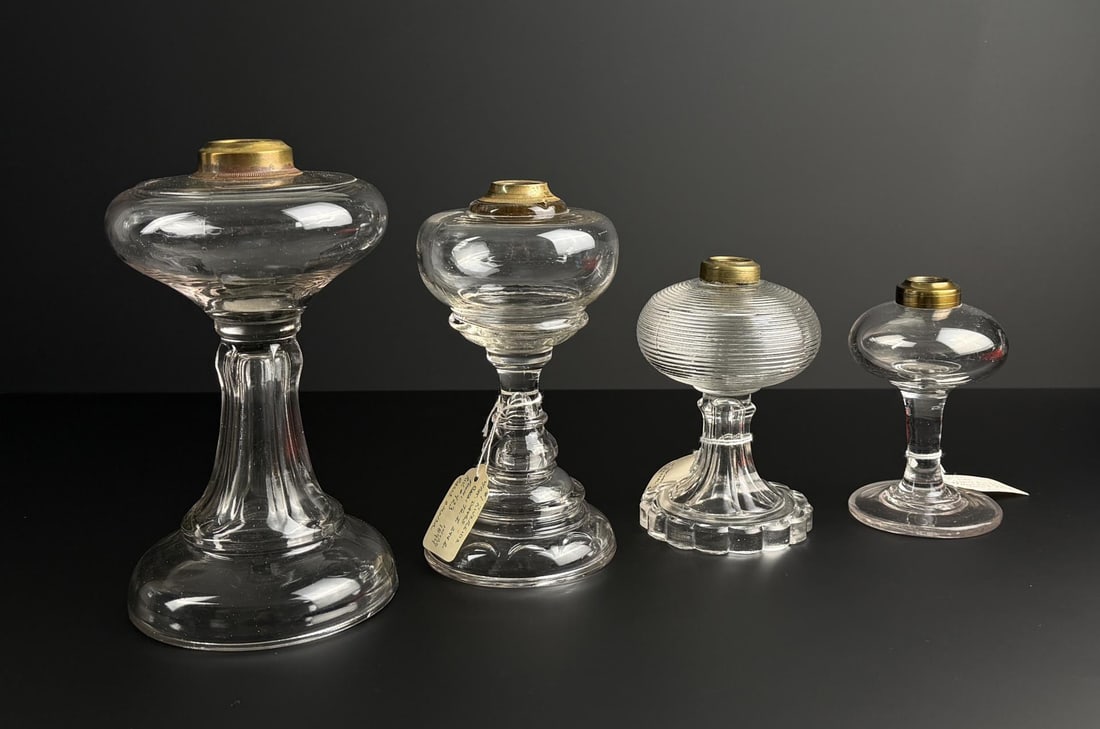 19th Century Glass Kerosene Lamps: Largest is 9 1/2" tall with a 4 1/2" base. One has a riverside pattern with patent date of 1894. One has a brass collar with two thin lines and a lace pattern base made by Atterbury. One has a