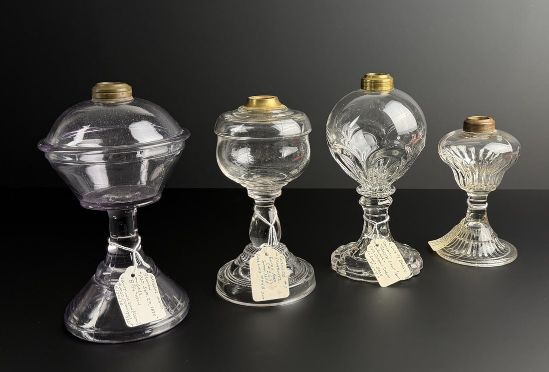Mid 19th Century Glass Whale Oil Lamps: Largest is 9" tall. Left is a purple tint inverted dome tube lamp, flint glass, form is classic late camphene/early kerosene transitional. Second is a ribbed base with round font riverside lamp. Third