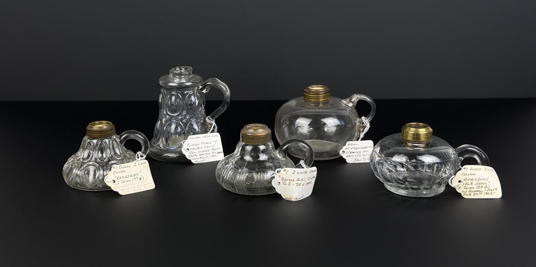 19th Century Kerosene Flint Glass Finger Lamps: Nice grouping. Largest is 4 3/8" tall. One shows a ringed oval pattern, 4 of the 5 Lamps have Brass 2 Line Collars and the other is missing its collar.